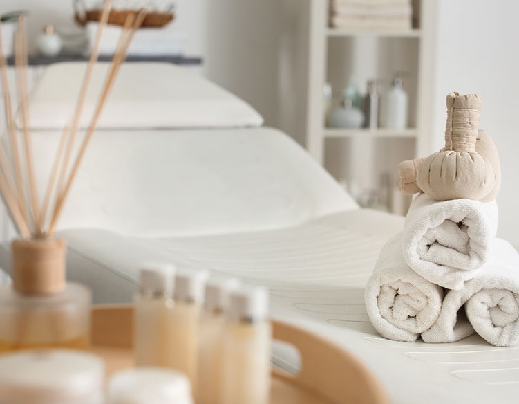 Several towels rolled up on the end of a massage bed