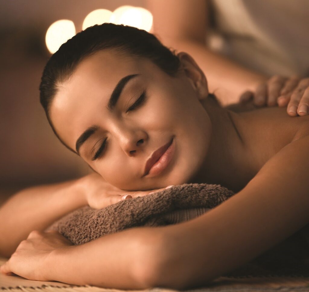 Brunette girl laying on her stomach receiving a massage in a spa